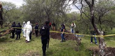 Peritos forenses acompañados de policías ministeriales, en la zona de donde han exhumado cuerpos de fosas clandestinas hoy en el municipio de Villamar en Michoacán. / EFE