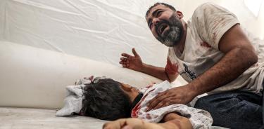 Un palestino llora frente al cadáver de su sobrino en el hospital Al Shifa de Gaza. En tres días de bombardeos israelíes han muerto 140 menores en la Franja