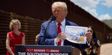 El candidato presidencial republicano Donald Trump sostiene un gráfico de cifras de inmigración mientras habla durante su visita a la frontera sur de EU en Arizona