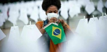 Una voluntaria ayuda a colgar pañuelos blancos durante un homenaje a las miles de víctimas mortales de Covid-19 en Río de Janeiro