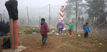 Niños refugiados miran desde el lado bielorruso a soldados polacos al otro lado de la frontera (EFE)