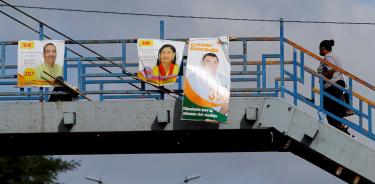 Una mujer camina por un puente antipeatonal donde han instalado carteles políticos, el martes 23 de noviembre en Tegucigalpa.