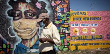 Una persona camina frente a un mural sobre la COVID-19 en el barrio de Soweto, Johanesburgo, el martes 30 de noviembre de 2021.