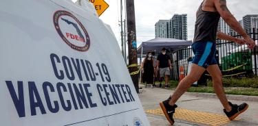 Personas pasan cerca de un centro de vacunación contra la COVID-19 en Miami, en una imagen de archivo.