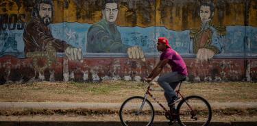 Un hombre pasa frente a un mural donde se observa la imagen de Ernesto 
