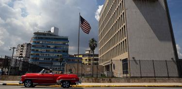 Un coche clásico circula enfrente de la embajada estadunidense en La Habana durante los años de deshielo.