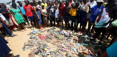 Personas contemplan una montaña de zapatos de las víctimas de la estampida en Monrovia, Liberia, este jueves 20 de enero.