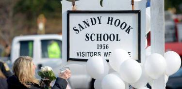 Andrea Jaeger lleva flores y una vela en el exterior de la escuela Sandy Hook, en Newtown, Connecticut