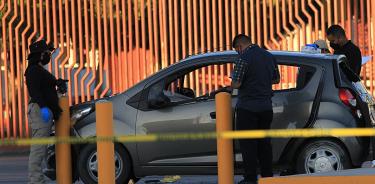 Policías estatales y de investigación revisan un vehículo donde viajaban cinco personas que fueron asesinadas en Ciudad Juárez
