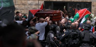 Granaderos israelíes cargan contra los palestinos que portaban el féretro durante el funeral por la periodista Shileen Abu Akleh, este viernes 13 de mayo de 2022 en Jerusalén.