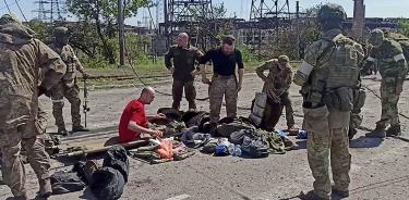 Captura de video que muestra a militares ucranianos de Azovstal, en Mariúpol, preparándose para ser evacuados y vigilados por soldados rusos, este miércoles 18 de mayo de 2022