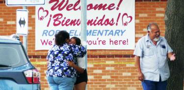 Una joven y otra mujer se abrazan frente a la escuela primaria Robb de Uvalde, Texas, tras el tiroteo que dejó 18 niños y 3 adultos muertos, este martes 24 de mayo de 2022.