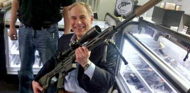 Greg Abbott, gobernador republicano de Texas, posa sonriente con un enorme rifle de asalto el 25 de noviembre de 2016.