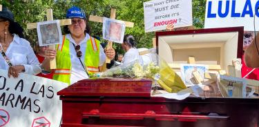 Personas protestan contra la convención de la NRA mostrando fotografías de varios niños fallecidos en el tiroteo de Uvalde, junto a un féretro, este viernes 27 de mayo en Houston, Texas.