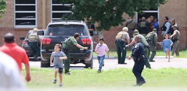 Agentes de policía ayudan a evacuar a niños y niñas a través de una ventana en la escuela primaria de Uvalde, Texas, durante el tiroteo, el martes 24 de mayo de 2022.