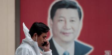Un hombre en un traje protector pasa frente a un retrato del presidente Xi Jinping en Shanghái, el lunes 23 de mayo de 2022.