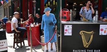 Londienses beben en un pub junto a un retrato en cartón de la reina Isabel II durante los festejos de su Jubileo de Platino, este viernes 3 de junio.