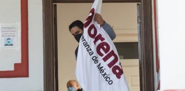 Un hombre acomoda una bandera de Morena