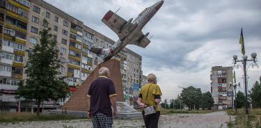 Dos personas caminan por las calles de Lisichansk, el 18 de junio de 2022, mientras se desarrollaban combates en la vecina Severodonetsk.