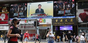 Gente camina en la calle frente a una pantalla gigante que muestra un mensaje del dictador chino, Xi Jinping, este viernes 1 de julio de 2022 en Hong Kong.