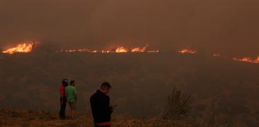 Personas observan el fuego que consume Penteli, en las afueras de Atenas, Grecia, este martes 19 de julio de 2022.