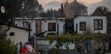 Vecinos de A Veiga da Cascallá, en Ourense, España, ante una vivienda arrasada por las llamas este martes 19 de julio de 2022.