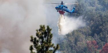 Un helicóptero suelta agua sobre el incendio forestal Oak Fire, cerca del parque nacional Yosemite en California, el 24 de julio de 2022.
