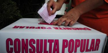 Una mujer introduce su papeleta donde emitió su voto dentro de la Consulta Ciudadana