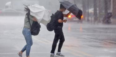 Dos personas intentan protegerse de la fuerte lluvia mientras cruzan un paso de peatones en Seúl, Corea del Sur, este lunes 8 de agosto de 2022.