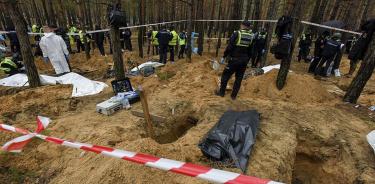 Trabajadores de emergencias ucranianos trabajan en la exhumación de cuerpos en una de las fosas halladas este viernes 16 de septiembre de 2022 en Izium.