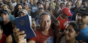 Migrante cubano muestra pasaporte en un paso fronterizo entre México y EU