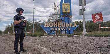 Un zapador ucraniano resguarda un enorme poste que lee “Oblast de Donetsk” y una señal de “Peligro: Minas”, este martes 20 de septiembre de 2022.