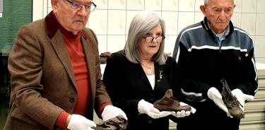 Bogdan Barnikowski, superviviente de Auschwitz, Phylis Greenberg Heideman, presidenta de la organización Marcha de los Vivos, y Arie Pinsker, superviviente de Auschwitz, posan con zapatos que pertenecieron a niños asesinados en el campo nazi de Auschwitz.