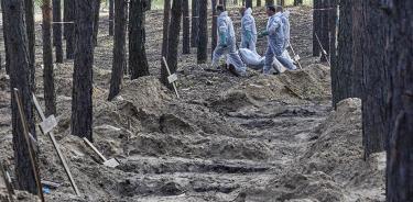 Forenses ucranianos trasladan un cuerpo exhumado de las fosas comunes descubiertas en Izium tras la marcha de los rusos, el 19 de septiembre.