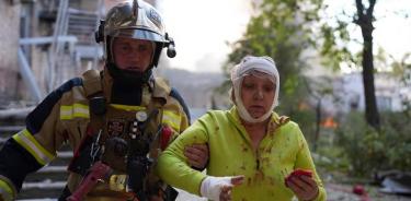 Un bombero ayuda a una mujer que resultó herida durante el bombardeo ruso a Kiev