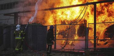 Bomberos tratan de apagar un incendio causado por un bombardeo ruso, este martes 18 de octubre de 2022 en Kiev.