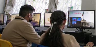 Dos jóvenes utilizan computadoras con internet