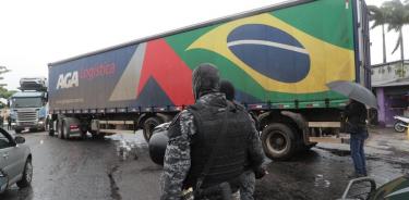 Un agente de la policía observa impasible cómo un camión se dispone a bloquear una carretera en el estado de Río de Janeiro
