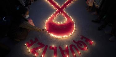 Mujeres y niños del hogar de rehabilitación 'Maiti Nepal', encienden este miércoles velas con forma del símbolo internacional del SIDA, en vísperas del Día Mundial del SIDA, en Katmandú, Nepal.