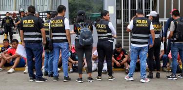 Integrantes de la Policía Nacional de Perú (PNP) vigilan a un grupo de personas detenidas en el campus de la Universidad Nacional Mayor de San Marcos