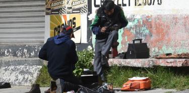 Dos jóvenes boleros se esmeran lustrando calzado en calles de Toluca