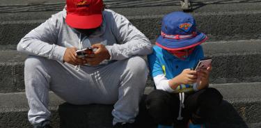 Un par de niños se entretienen con sus respectivos celulares
