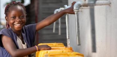 Marie, de 7 años, extrae agua de una fuente construida con el apoyo de UNICEF en el distrito de Buhene en Goma, República Democrática del Congo. Una erupción volcánica en 2021 dañó las infraestructuras del barrio, incluyendo su red de suministro de agua