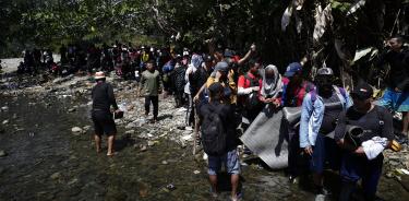 Migrantes hacen fila para pasar un río en la localidad selvática de Bajo Chiquito, en Panamá