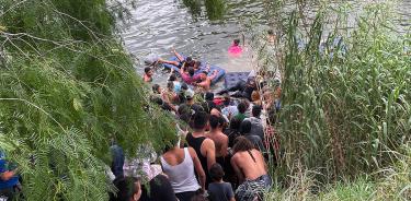 Un grupo de migrantes intentan cruzar el Río Bravo con un inflable hoy, en la ciudad de Matamoros en Tamaulipas