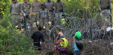 Militares observan a migrantes luego de cruzar el río Bravo para intentar ingresar a EU.