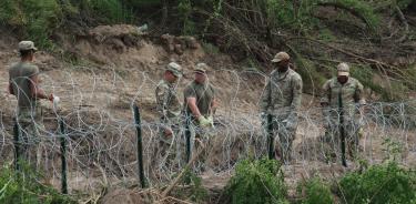 Soldados estadounidenses charlan relajados frente a una alambrada en el río Bravo a la altura de Matamoros, Tamaulipas
