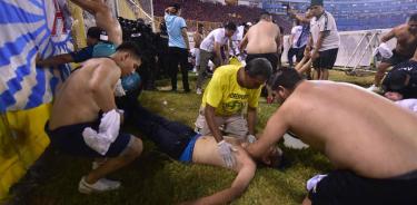 Espectadores tratan de reanimar a un aficionado gravemente herido por la estampida en el estadio de San Salvador