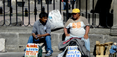 Dos albañiles desempleados esperan ofertas de trabajo en el costado de la Catedral Metropolitana en la Ciudad de México.
