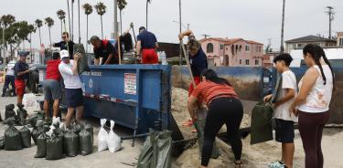 Residentes en Long Beach, sur de Los Ángeles, llenan sacos de arena para evitar que se inunden sus casas durante el paso de Hilary